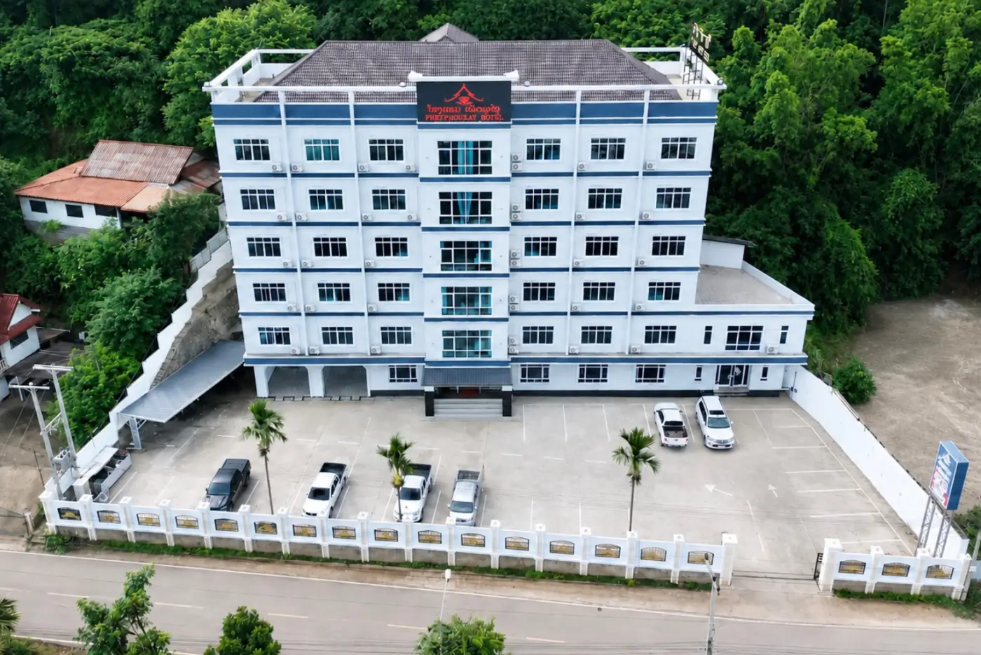 Phetphouxay Hotel seen from the air — a six-storey building with its car park and the hills behind