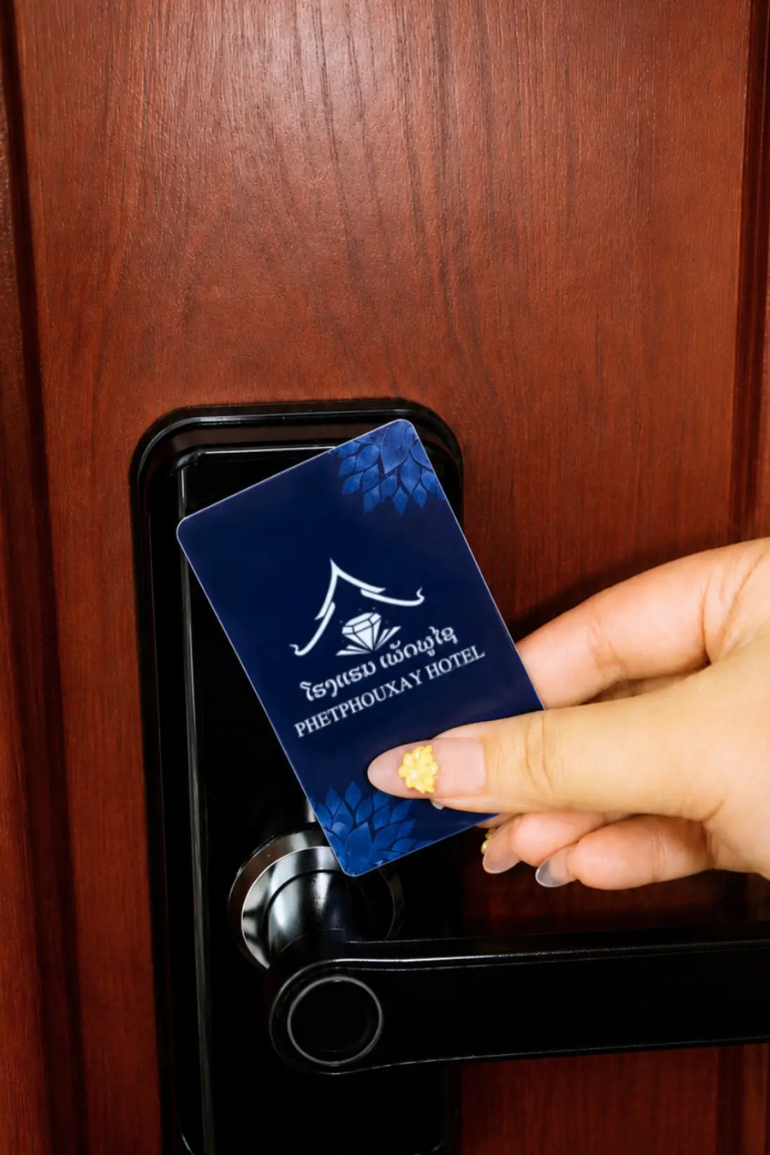 A guest tapping a Phetphouxay Hotel key card on a room door
