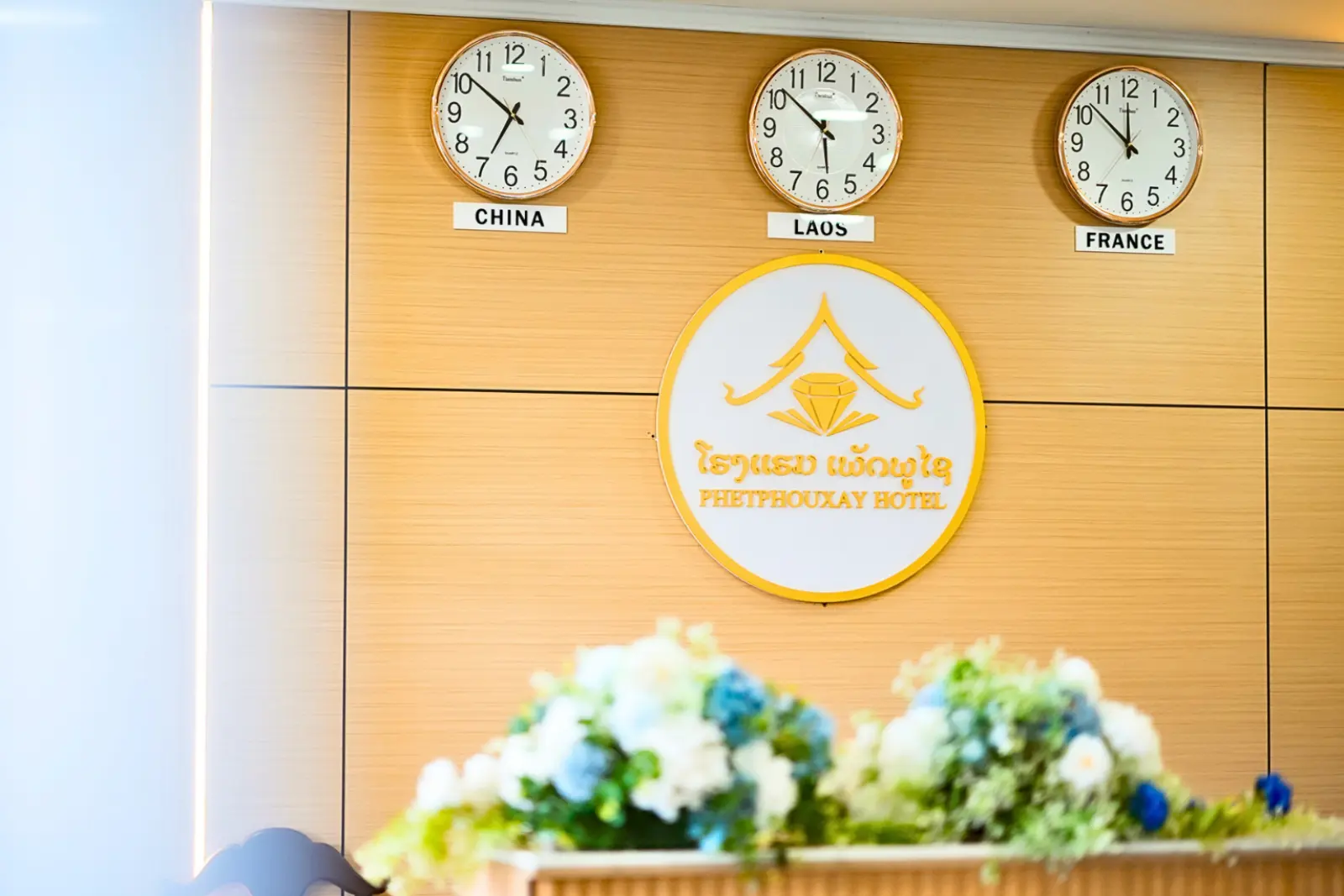 Hotel lobby with the Phetphouxay Hotel emblem and clocks for China, Laos and France