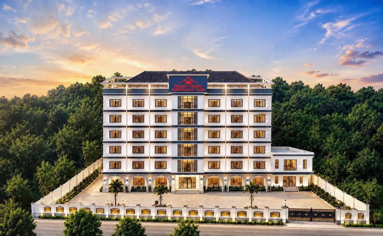 Phetphouxay Hotel at dusk, lit against the trees