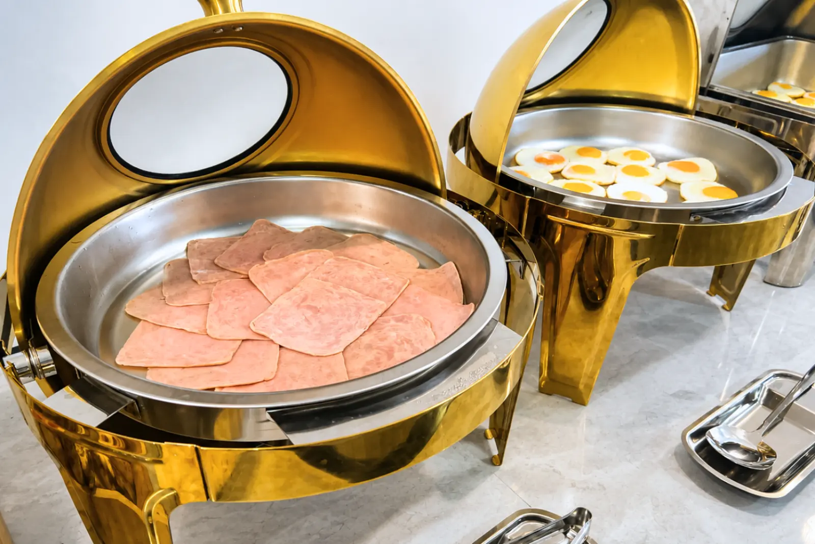 Sliced ham in a gold chafing dish on the buffet