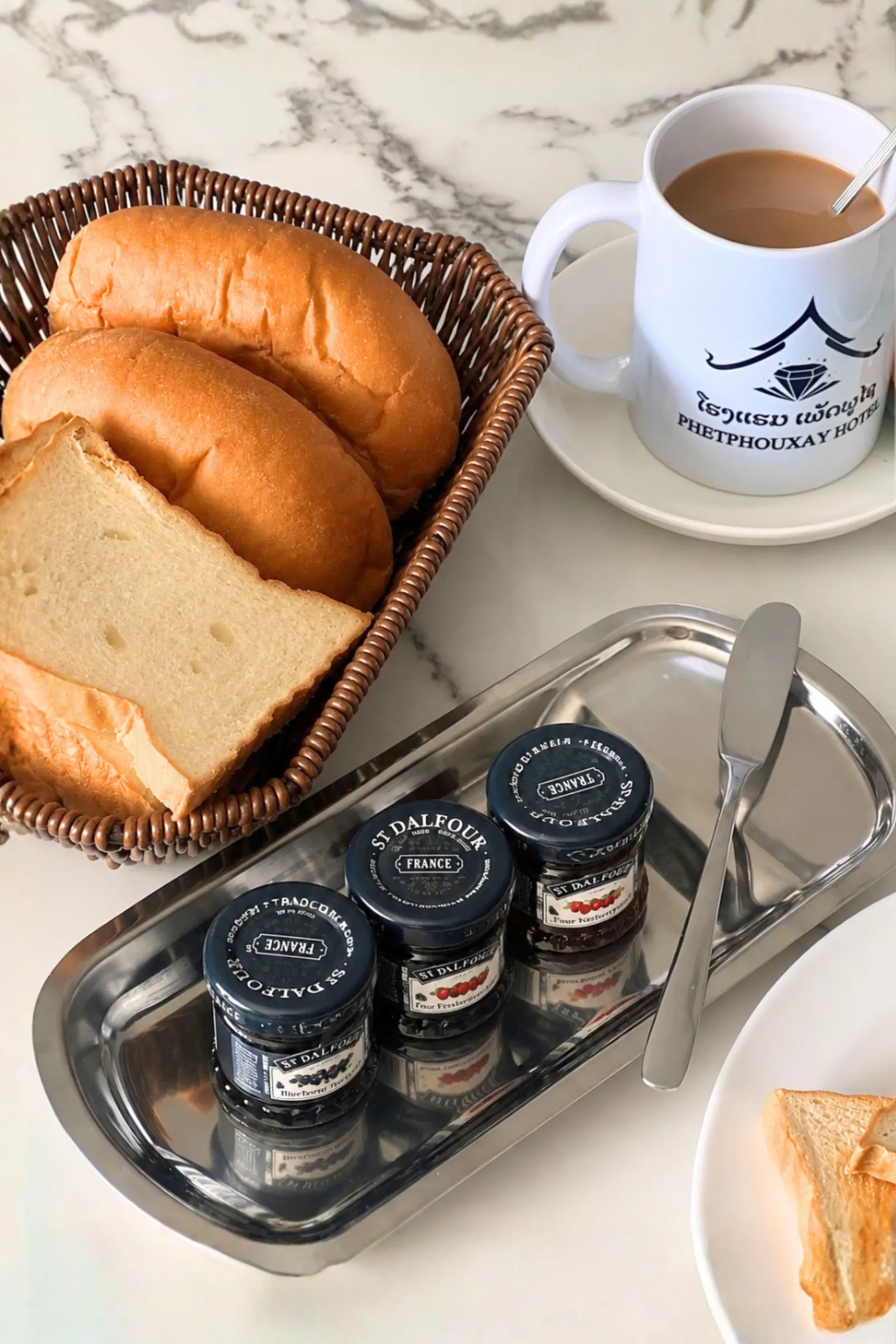 Bread basket with jam pots and a Phetphouxay Hotel coffee cup
