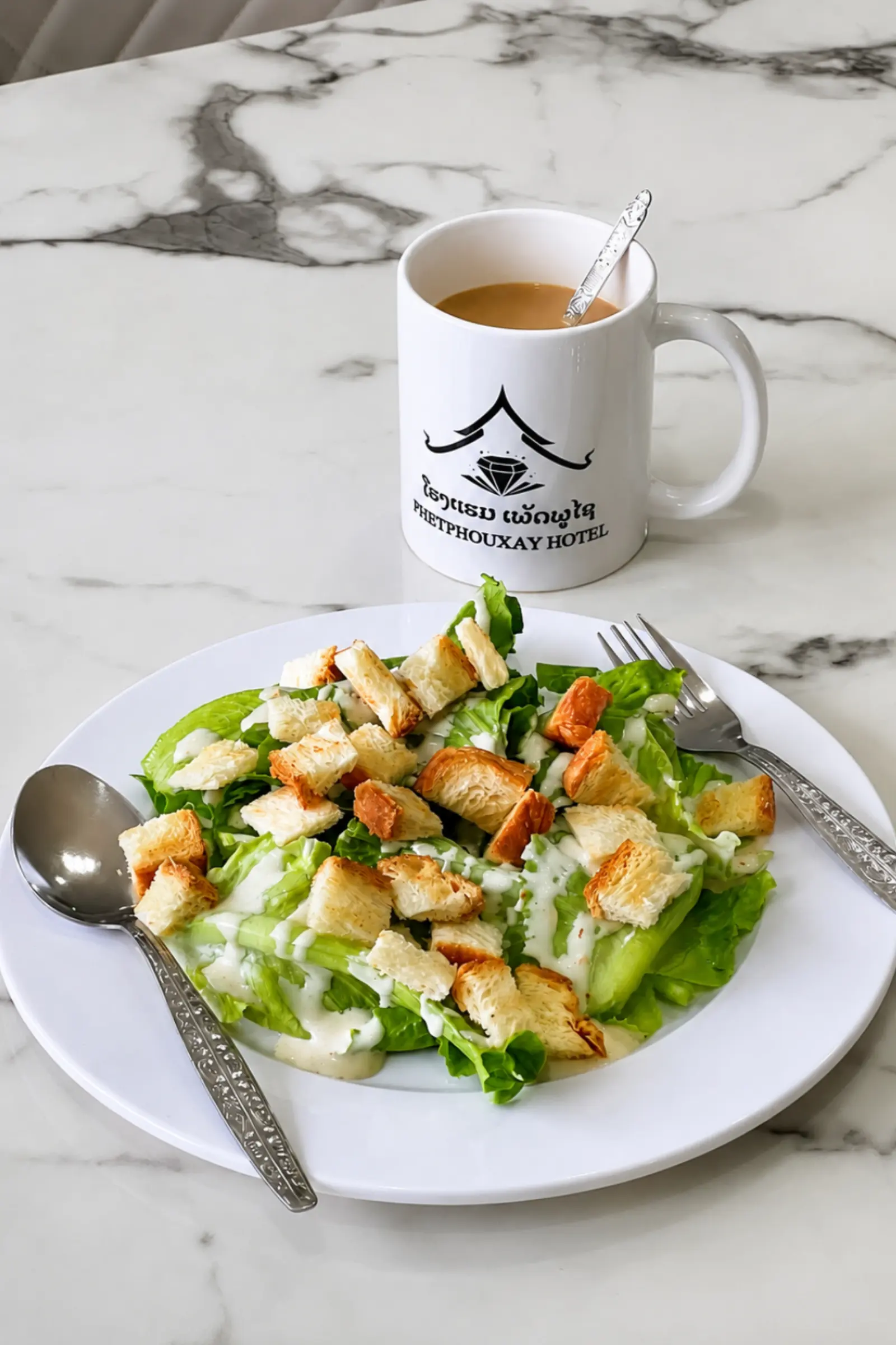 Garden salad with croutons and a Phetphouxay Hotel coffee cup