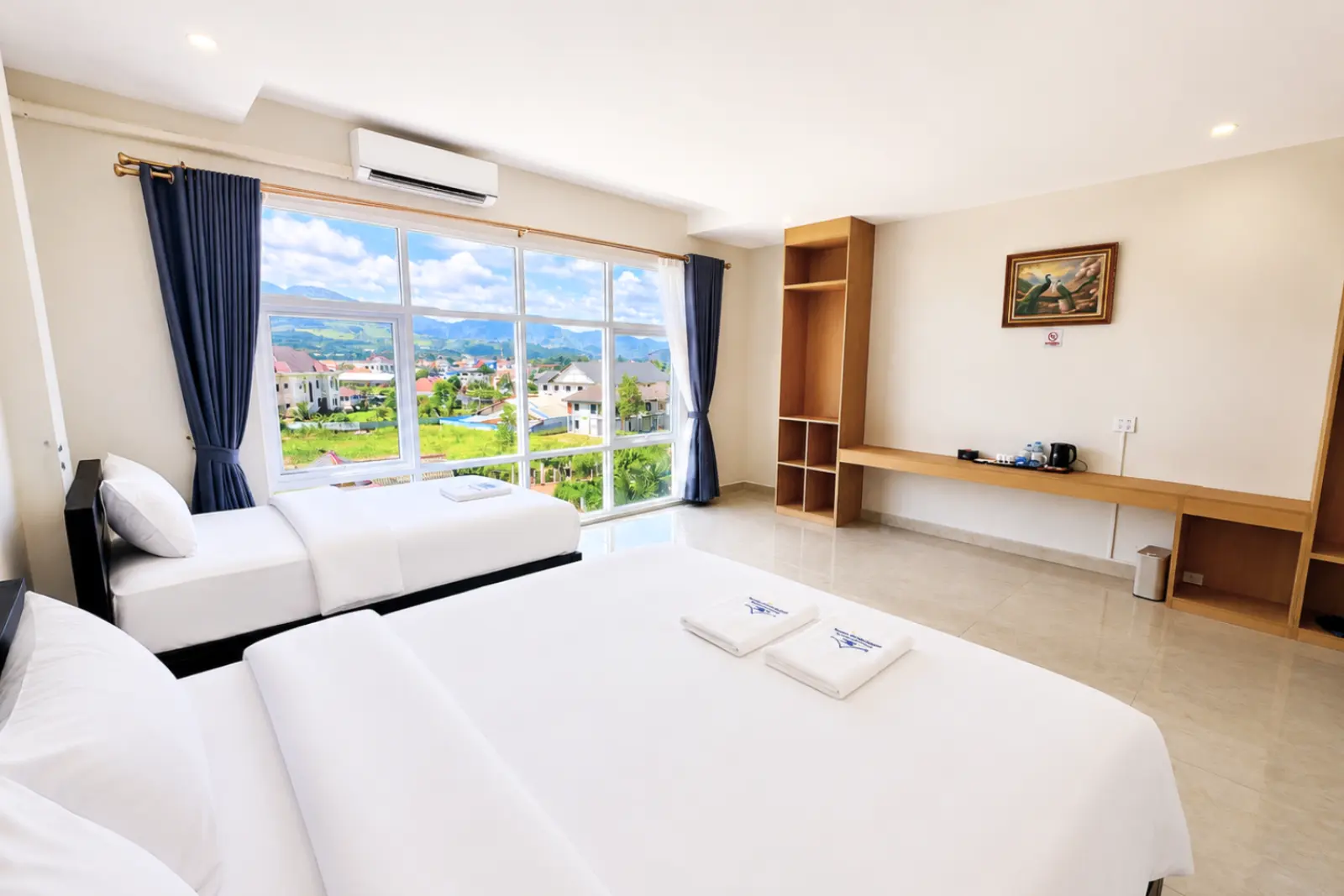 Family room with a double and a single bed beside a wide window over the valley