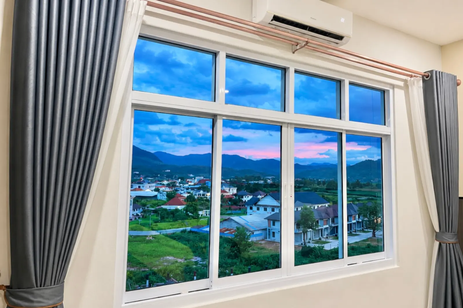 Guest-room window at dusk, with pink cloud over the town and the mountains